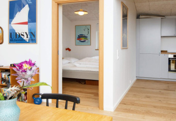 Vue sur la chambre et la cuisine d'une maison de vacances à Sydals, Danemark, avec une déco moderne et affiches colorées.