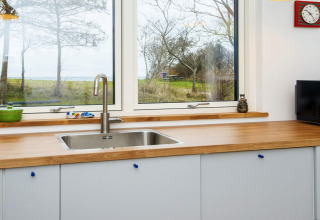 Moderne spoelbak met houten werkblad en groot raam in een vakantiehuis in Sydals, Denemarken.