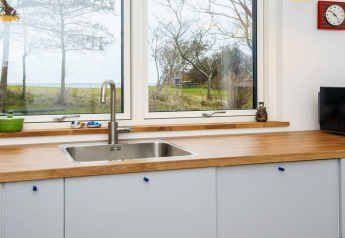 Évier de cuisine moderne avec plan de travail en bois et vue sur la nature en maison de vacances à Sydals.