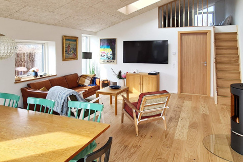 Modernes Wohnzimmer in einer Ferienlodge mit Holzmöbeln, TV, Sofa und Oberlicht in Sydals, Dänemark.