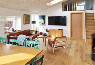 Moderne woonkamer in vakantiehuis in Sydals, Denemarken, met houten meubels, bank, tv en dakraam.