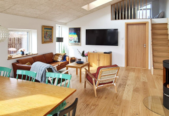 Gezellige leefruimte in een vakantiewoning in Sydals, Denemarken, met houten meubels, bank, tv en dakraam.