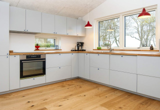 Moderne keuken met lichte kasten en houten vloer in een luxueuze vakantiewoning in Sydals, Denemarken.