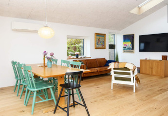 Bright living area in 5 star holiday home in Sydals, Denmark, featuring green chairs, sofa and TV.