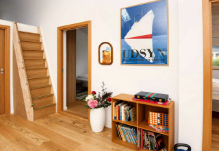 Intérieur d'un gîte moderne à Sydals au Danemark, escalier en bois, bibliothèque et déco murale.
