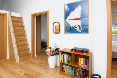 Casa vacanze moderna a Sydals, Danimarca, con scala in legno, libreria e arte murale colorata.