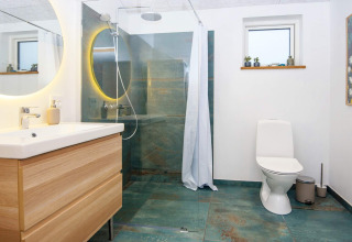 Bagno moderno nella casa vacanze a Sydals, Danimarca, con doccia, wc e mobile in legno.