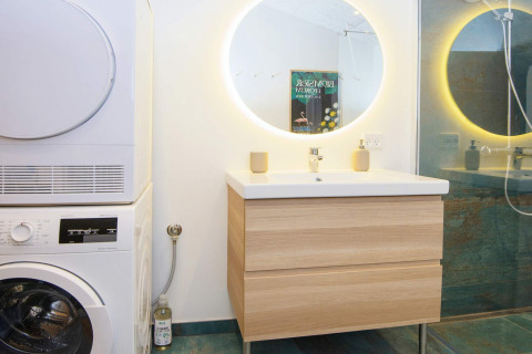 Moderne badkamer met wasmachine, droger, verlichte spiegel en douche in lodge in Sydals, Denemarken.