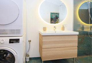 Moderne badkamer met wasmachine, droogkast, verlichte spiegel en douche in lodge te Sydals, Denemarken.