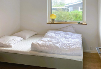 Camera luminosa con letto matrimoniale, piumoni e cuscini bianchi in una casa vacanza a 5 stelle a Sydals, Danimarca.