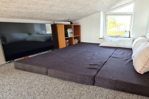 Accogliente mansarda presso ‘5 star holiday home in Sydals’, Danimarca, con letto, TV, libreria e finestra.