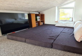 Ático acogedor en «5 star holiday home in Sydals», Dinamarca, con cama grande, TV y estantería junto a ventana.