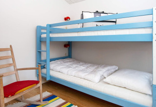 Et hyggeligt værelse på 5 stjernet feriehus i Sydals, Danmark, med blå køjeseng og gyngestol.