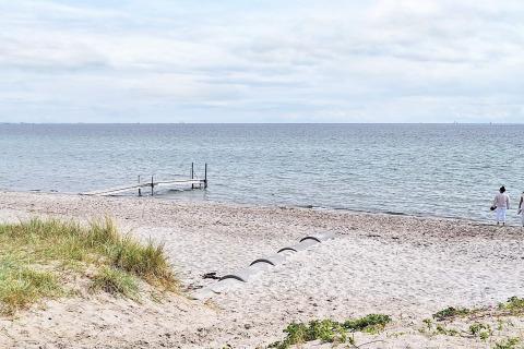 Strandzicht bij het 5-sterren vakantiehuis in Sydals, Denemarken, met steiger en persoon bij het water.