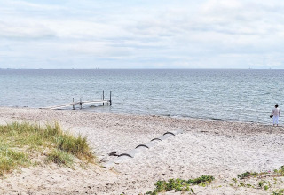 Strandzicht bij het 5-sterren vakantiehuis in Sydals, Denemarken, met steiger en persoon bij het water.
