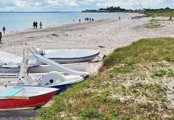 Strandbillede ved «5 stjernet feriebolig i Sydals», Danmark, med både, sand og gående mennesker.