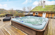 Vasca idromassaggio all’aperto su terrazza in legno presso un lodge con tetto erboso vicino a Tau, Danimarca.