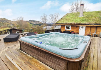 Buitenjacuzzi op houten terras bij lodge met groendak, omringd door natuur bij Tau, Denemarken.