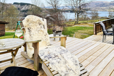 Houten terras bij lodge in Tau, Denemarken met comfortabele ligstoel, schapenvacht en meeruitzicht.