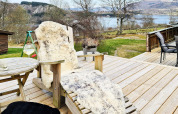 Houten terras bij lodge in Tau, Denemarken met comfortabele ligstoel, schapenvacht en meeruitzicht.
