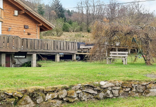 Holzhaus mit großer Terrasse, Gartenbank, Schaukeln und Grünanlage an der 12-Personen-Ferienhütte in Tau, Dänemark.
