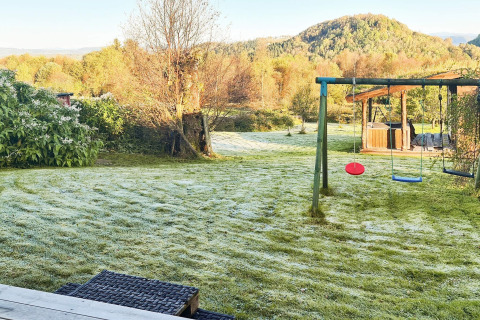 Bevroren grasveld met schommels bij 12-persoons vakantiehuis in Tau, Denemarken, omringd door natuur.