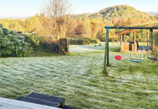 Jardín cubierto de escarcha y columpios en casa de vacaciones para 12 personas en Tau, Dinamarca, con naturaleza.