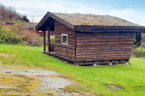 Pequeña cabaña de madera con techo de césped junto a la casa de vacaciones en Tau, Dinamarca.