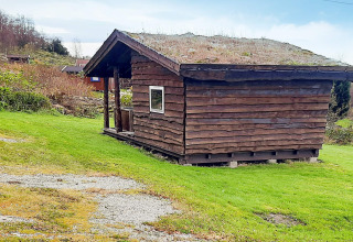 Kleine houten blokhut met groendak bij het 12-persoons vakantiehuis in Tau, Denemarken.