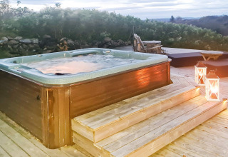 Vasca idromassaggio all'aperto con acqua fumante, terrazza in legno e lanterne nella casa vacanze 12 persone a Tau, Danimarca.