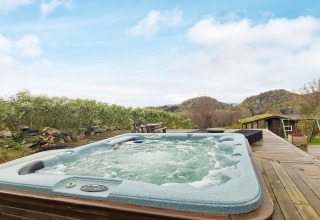 Außenwhirlpool auf Holzterrasse mit schöner Aussicht, bei 12-Personen-Ferienhaus in Tau, Dänemark.