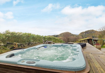Außenwhirlpool auf Holzterrasse mit schöner Aussicht, bei 12-Personen-Ferienhaus in Tau, Dänemark.