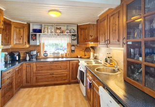 Gezellige keuken met houten kasten en moderne apparaten in 12-persoons vakantiehuis in Tau, Denemarken.