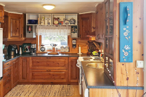 Gezellige houten keuken met moderne apparatuur en raam in een vakantiehuis voor 12 personen in Tau, Denemarken.