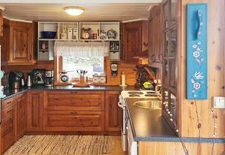 Gezellige houten keuken met moderne toestellen en raam in vakantiehuis voor 12 personen in Tau, Denemarken.