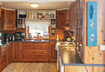 Gemütliche Holzküche mit modernen Geräten und Fenster in einem Ferienhaus für 12 Personen in Tau, Dänemark.