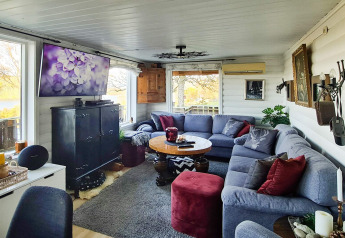 Knusse woonkamer in een vakantiehuis in Tau met grote hoekzetel, tv en zicht op het terras.