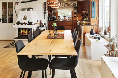 Essbereich mit sechs schwarzen Stühlen, Holztisch, Kamin und offener Küche in Tau, Dänemark.