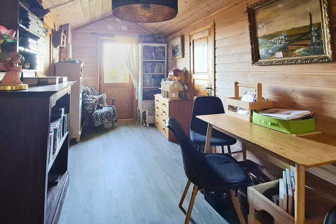 Træbeklædt opholdsstue med skrivebord, sorte stole, bogreoler og vindue i feriehus i Tau, Danmark.