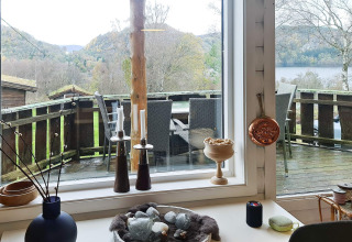 Vista dall’interno di un lodge a Tau, Danimarca, con terrazza, tavolo da pranzo e colline sullo sfondo.