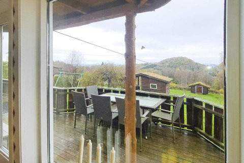 Vue depuis la fenêtre sur la terrasse avec table, chaises et cabanes d'une maison pour 12 à Tau.