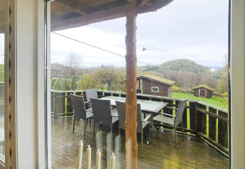Vista dalla finestra su terrazza con tavolo, sedie e casette del lodge per 12 persone a Tau.