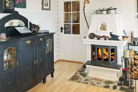 Gezellige woonkamer in een vakantiehuis in Tau, Denemarken, met zwarte kast en witte open haard.