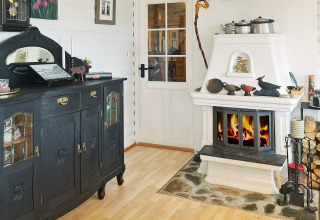 Gezellige woonkamer in een vakantiehuis in Tau, Denemarken, met zwarte kast en witte open haard.