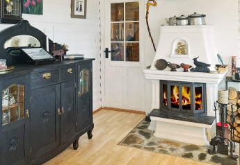 Gezellige woonkamer in een vakantiehuis in Tau, Denemarken, met zwarte kast en witte open haard.