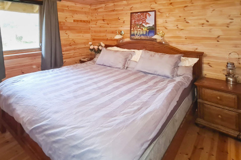 Dormitorio en la casa de vacaciones '12 personas en Tau' en Dinamarca con paredes de madera y gran cama.