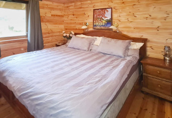 Slaapkamer in ‘12 persoons vakantiehuis in Tau’ in Denemarken met houten muren en groot bed.