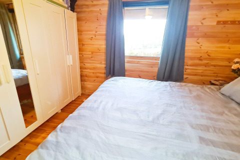 Soveværelse i træhytte med stor seng, gardiner og hvidt garderobeskab på '12 person holiday home in Tau', Danmark.