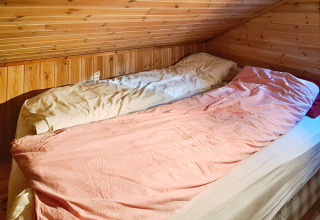 Due letti singoli in una mansarda accogliente con pareti in legno presso la 12 person holiday home in Tau, Danimarca.