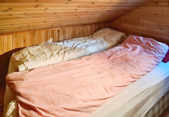 Twee eenpersoonsbedden in een knusse zolderkamer met houten wanden in het 12 persoons vakantiehuis in Tau, Denemarken.
